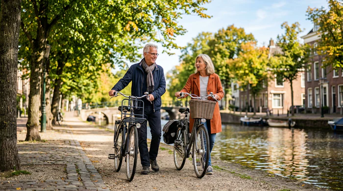 Ouder stel loopt met de fiets langs de gracht